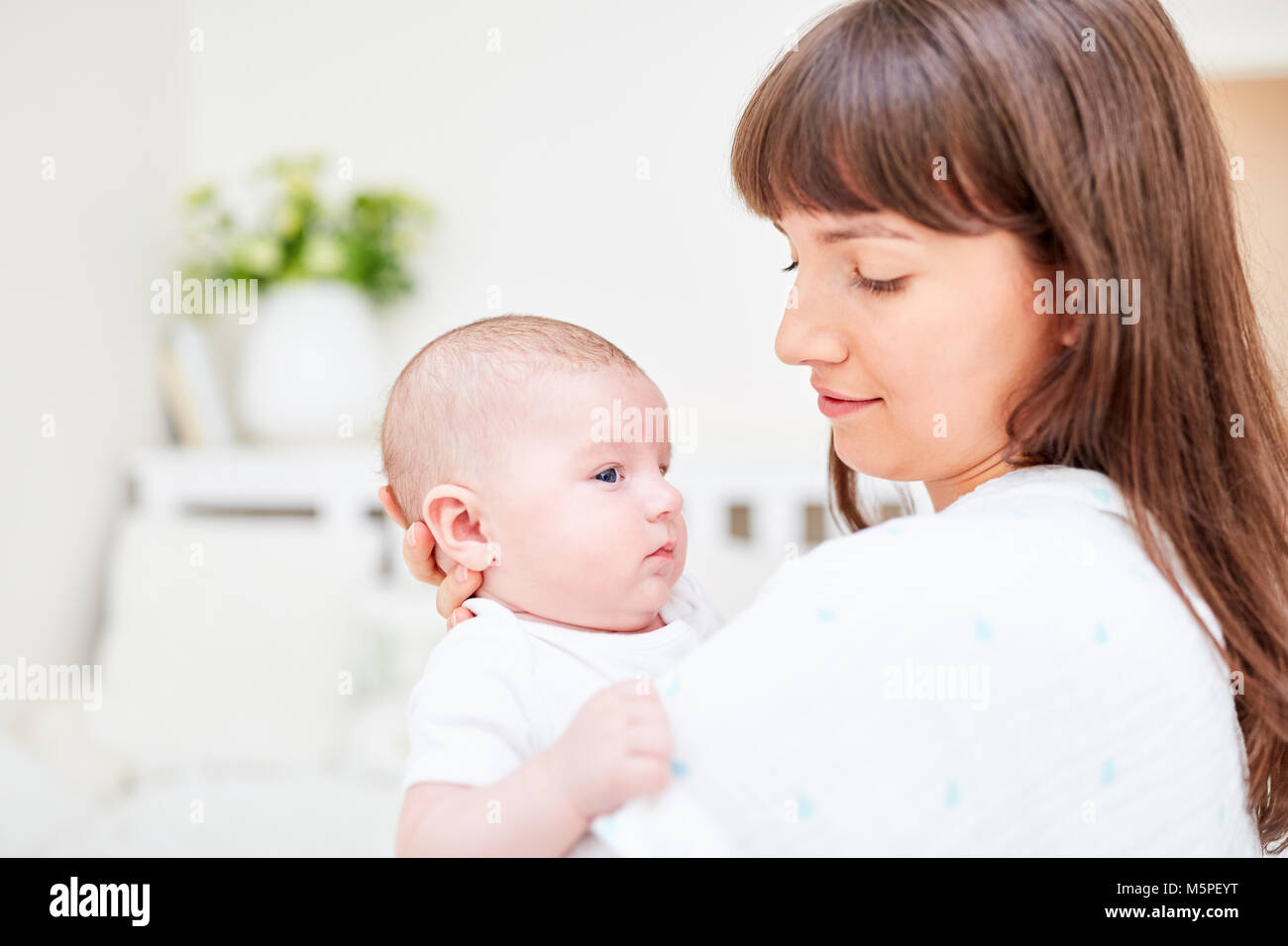 Woman as a loving mother holds her newborn baby tenderly in her arms Stock Photo