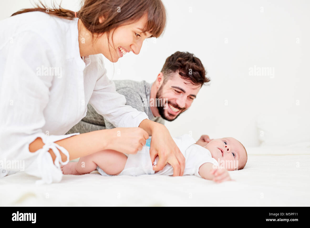 Caring parents make a diaper change with their little baby Stock Photo