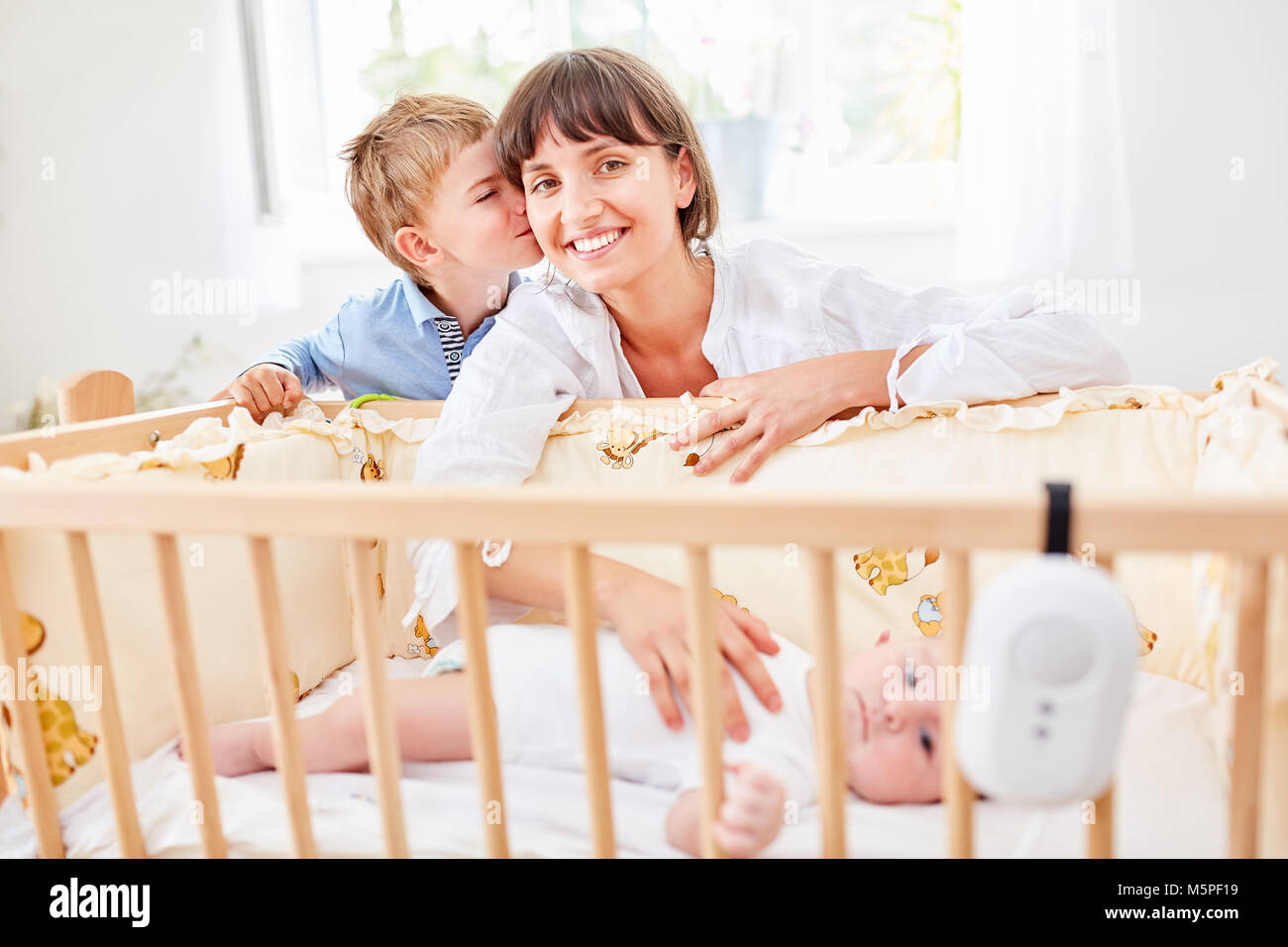 Little boy kisses his mother at the baby bed with newborn baby Stock Photo
