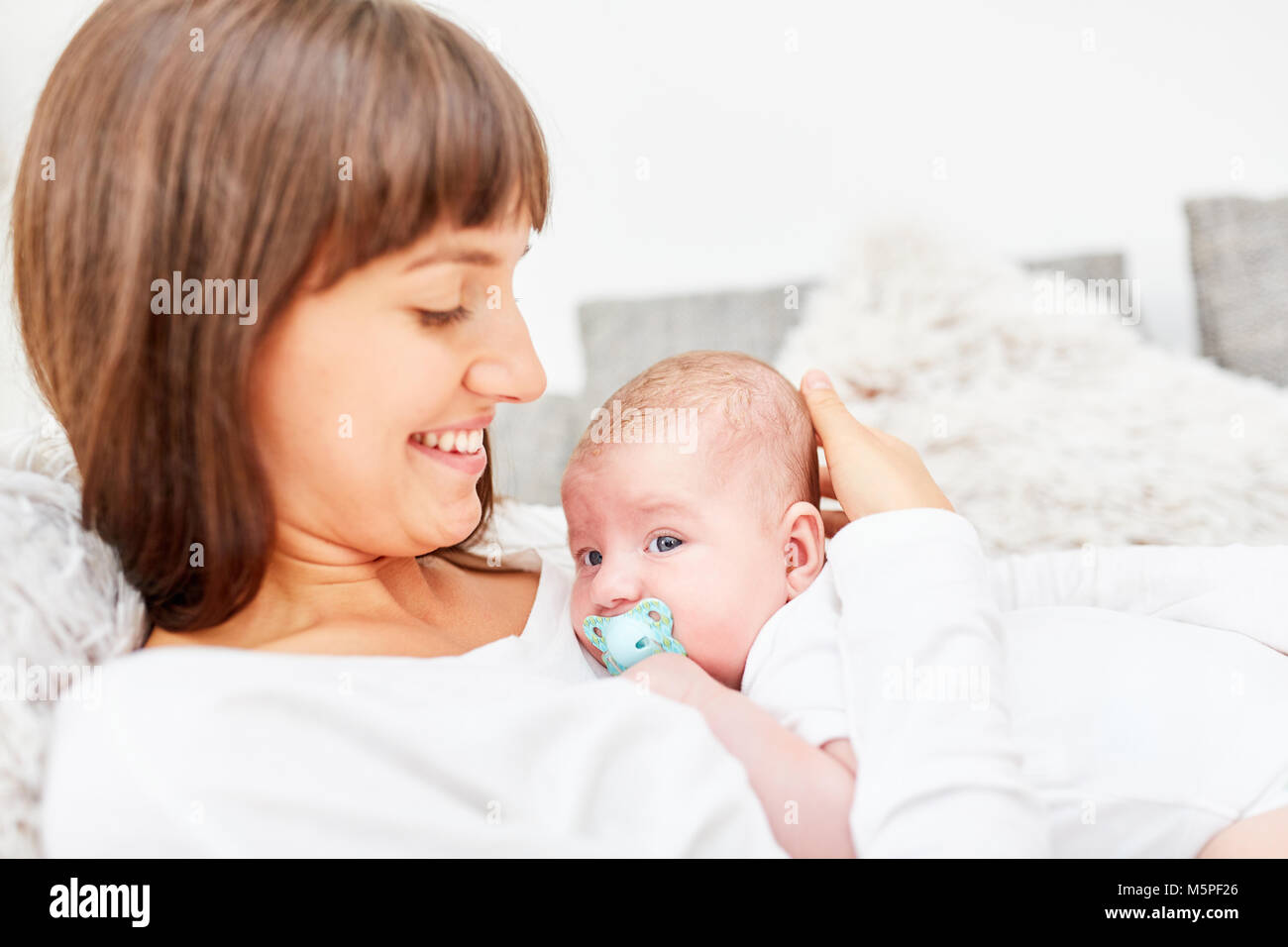Happy mother lovingly holds her baby in the arms at home on the sofa Stock Photo