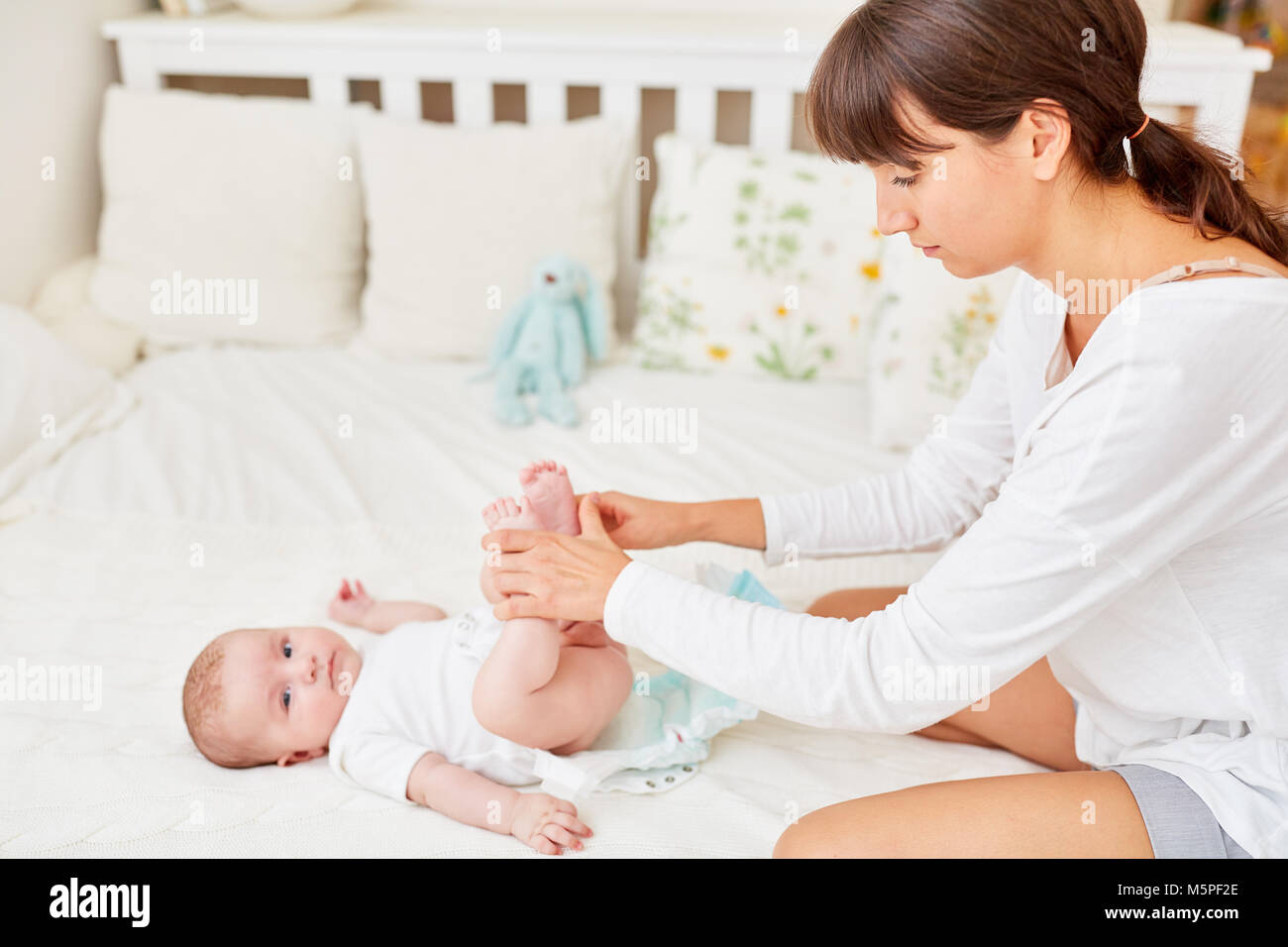 Young woman as a caring mother changes the diapers with her baby Stock Photo