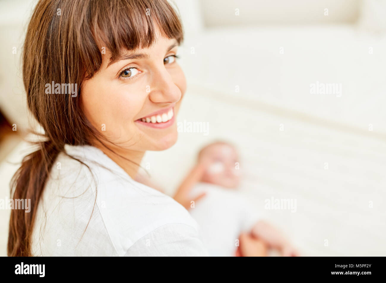 Young woman as a caring mother smiling while baby care Stock Photo