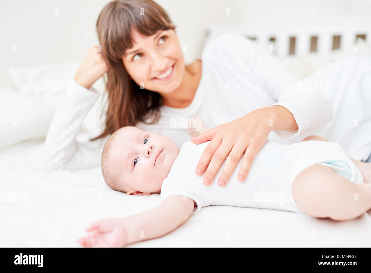 Happy and loving mother is lying next to her baby at home Stock Photo