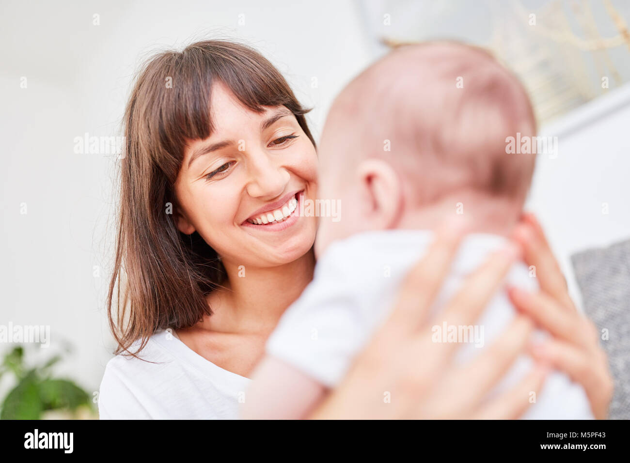 Young woman as a happy mother holds her little baby in her arms Stock Photo
