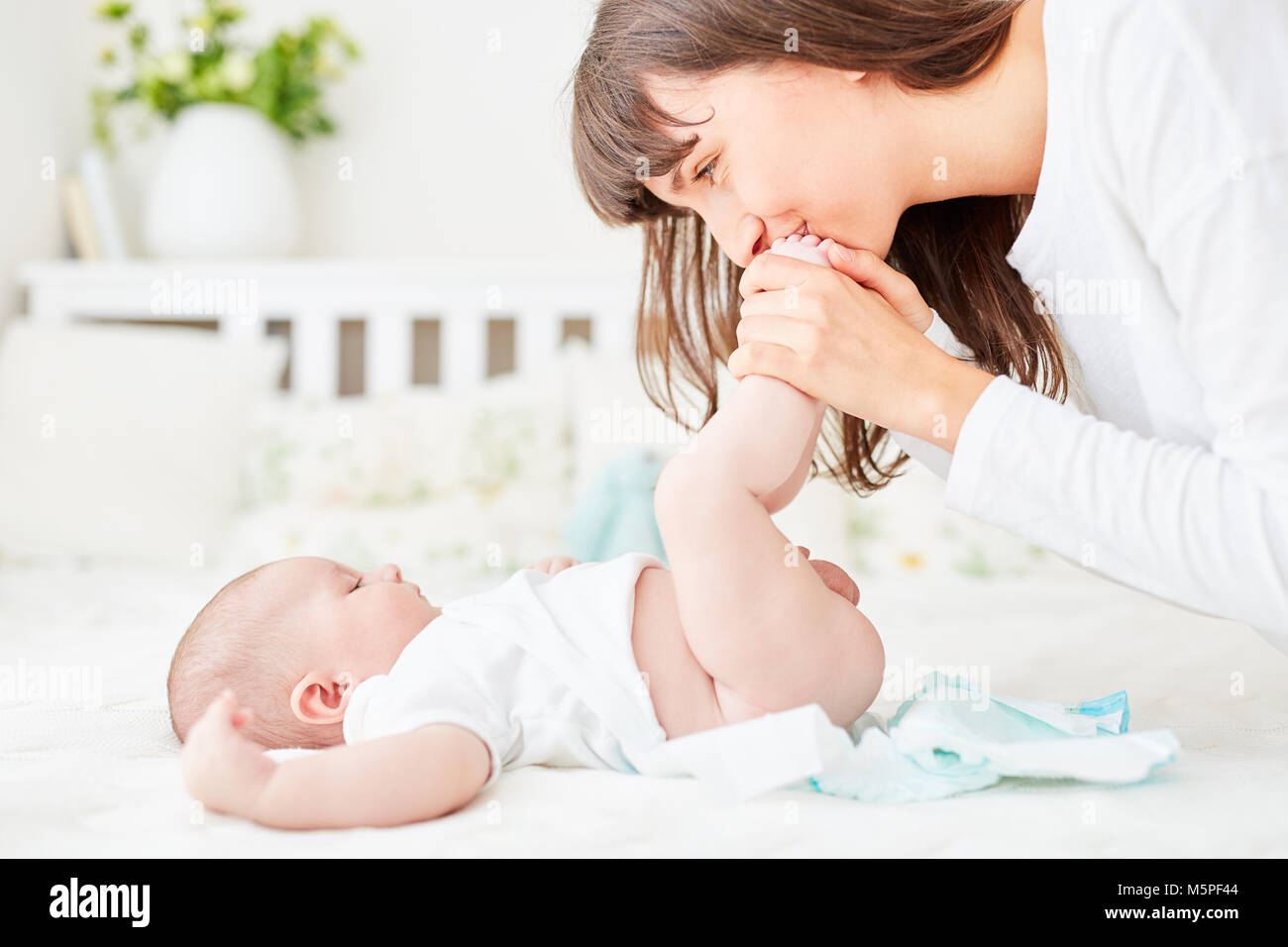 Caring mother changes the disposable diapers of her baby Stock Photo