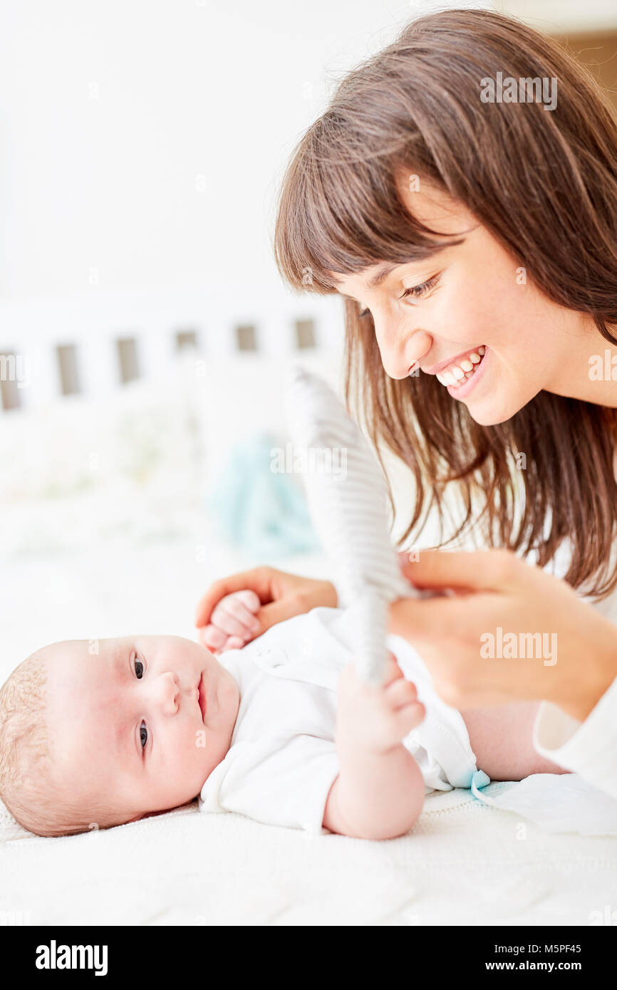 Woman as a smiling mother carefully changes the diapers with her baby Stock Photo