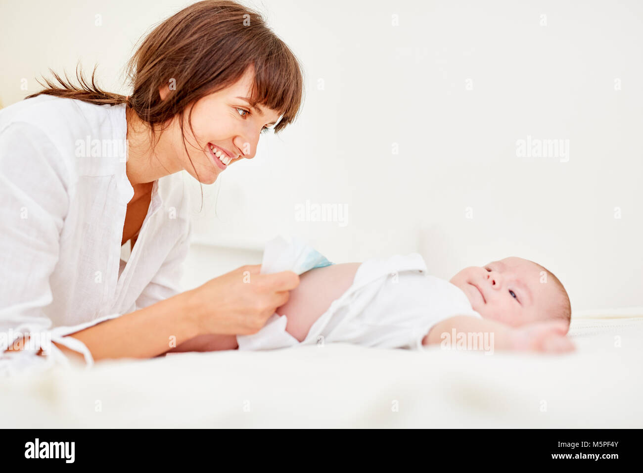 Smiling mother changes the diapers with her newborn baby Stock Photo