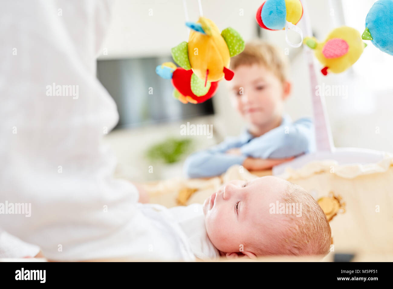 Brother watches the newborn baby falling asleep in the nursery Stock Photo