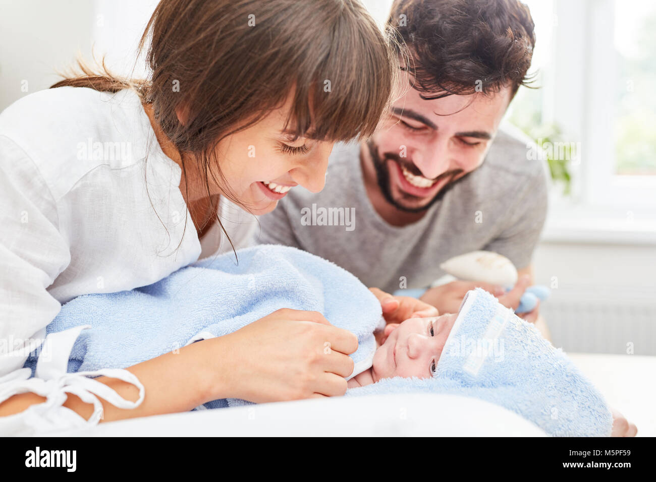 Father and mother happily look at their baby wrapped in a towel Stock Photo