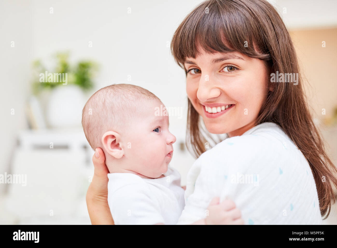 Young woman as a happy mother holds her newborn baby in her arms Stock Photo