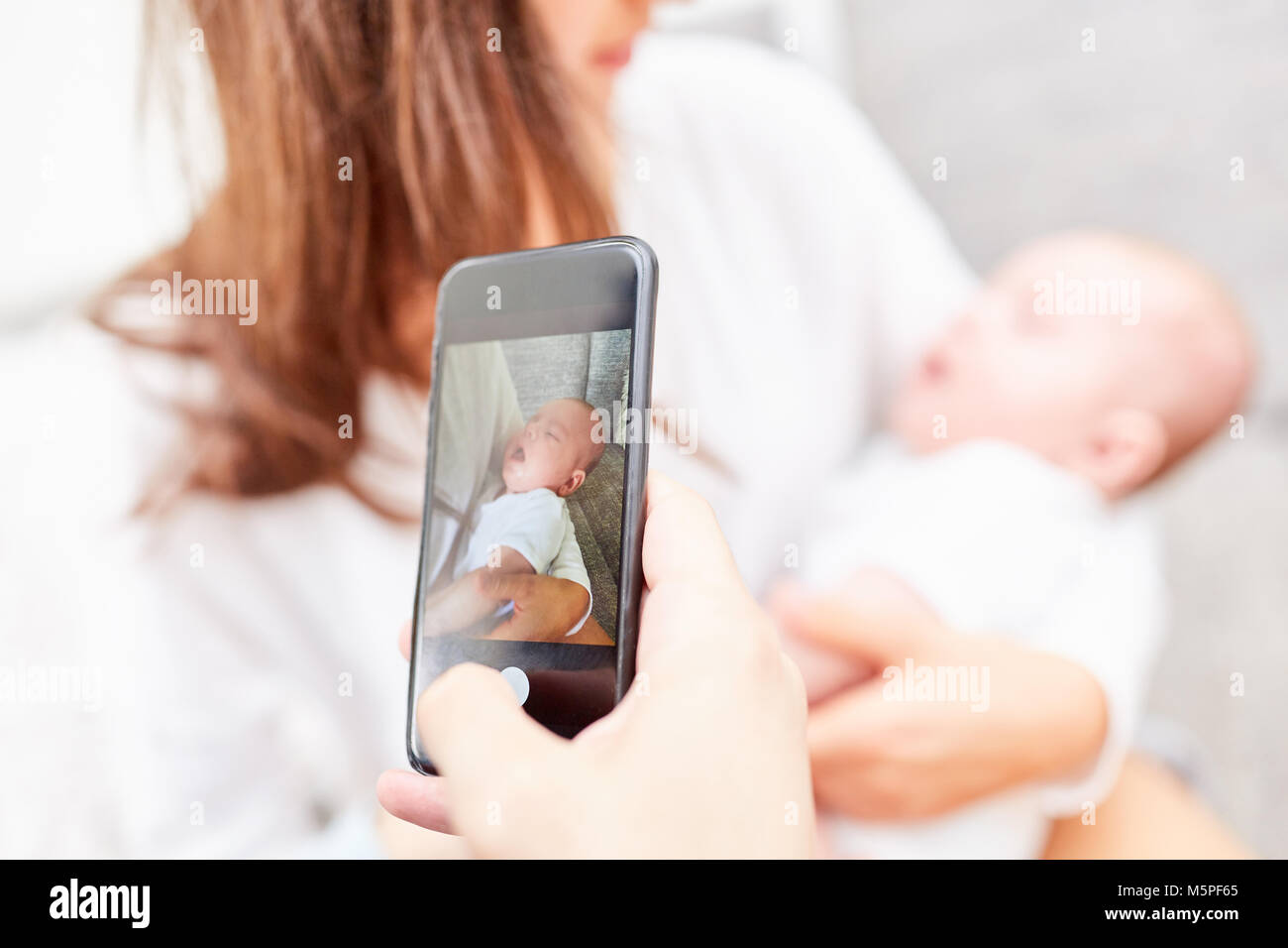 Father takes picture of baby and happy mother with the smartphone Stock Photo