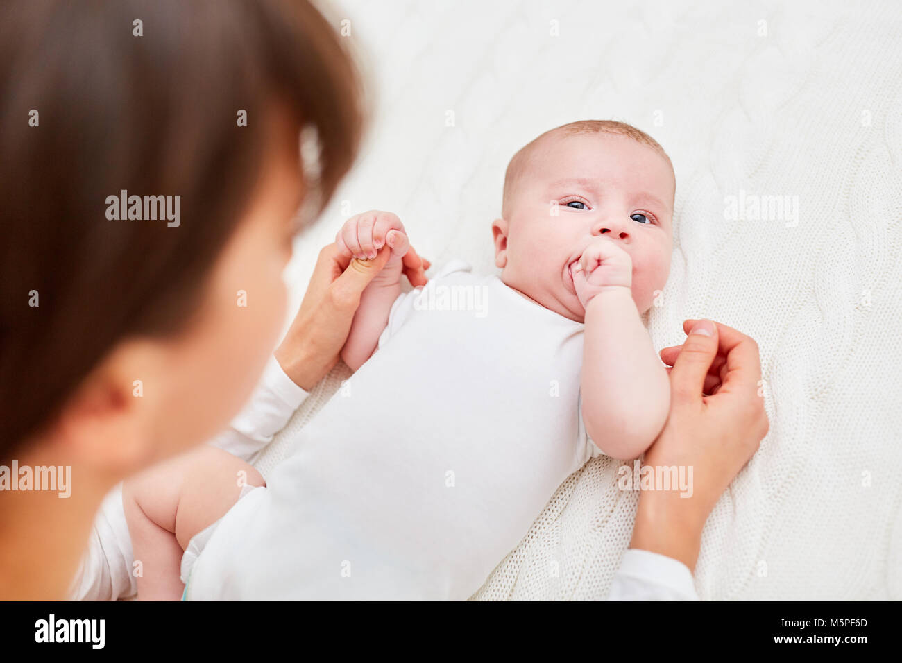 Newborn baby falling asleep lies with one finger in his hand Stock Photo