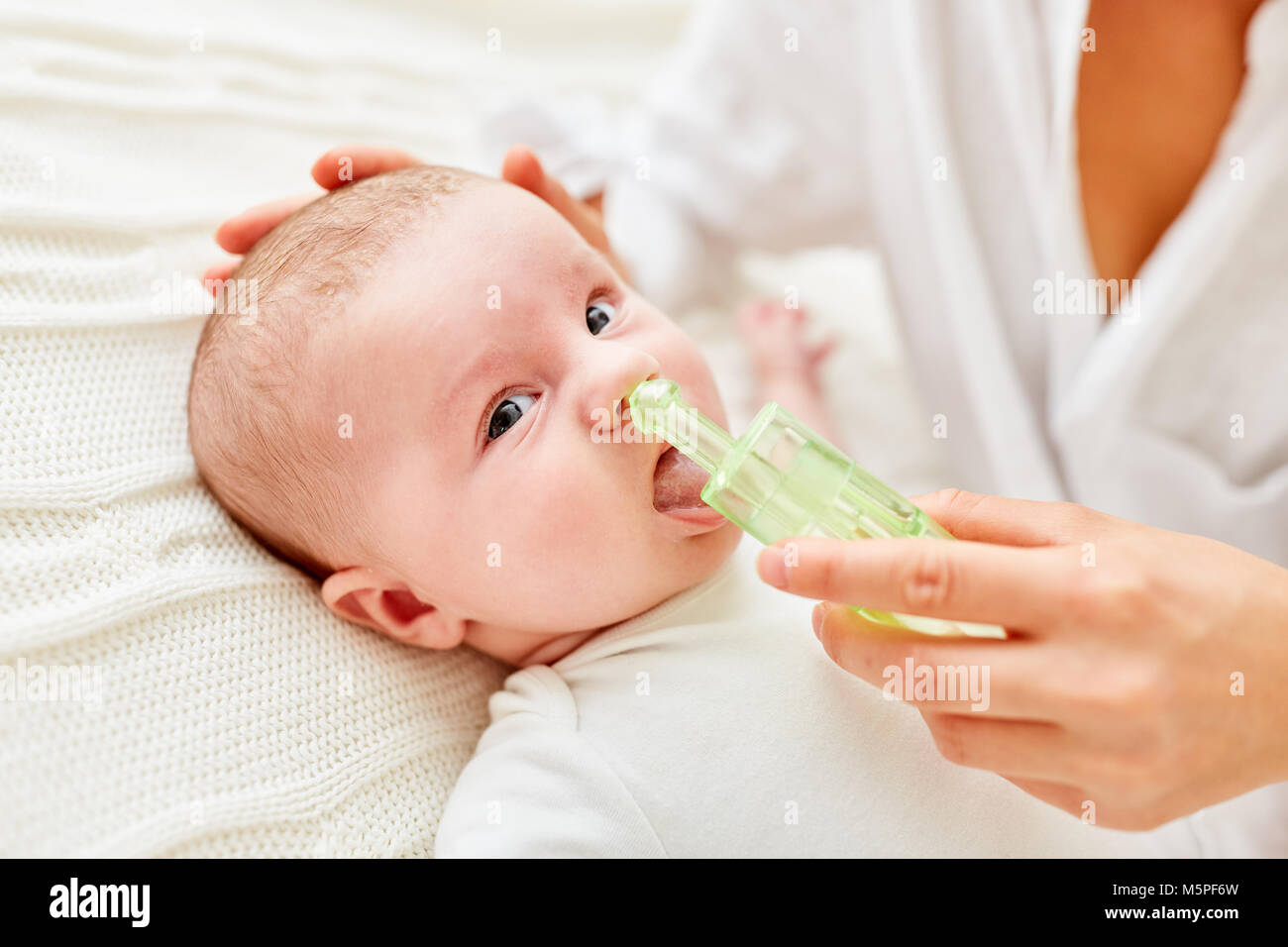 Mother cleans nose of little baby with a nasal aspirator for common cold Stock Photo