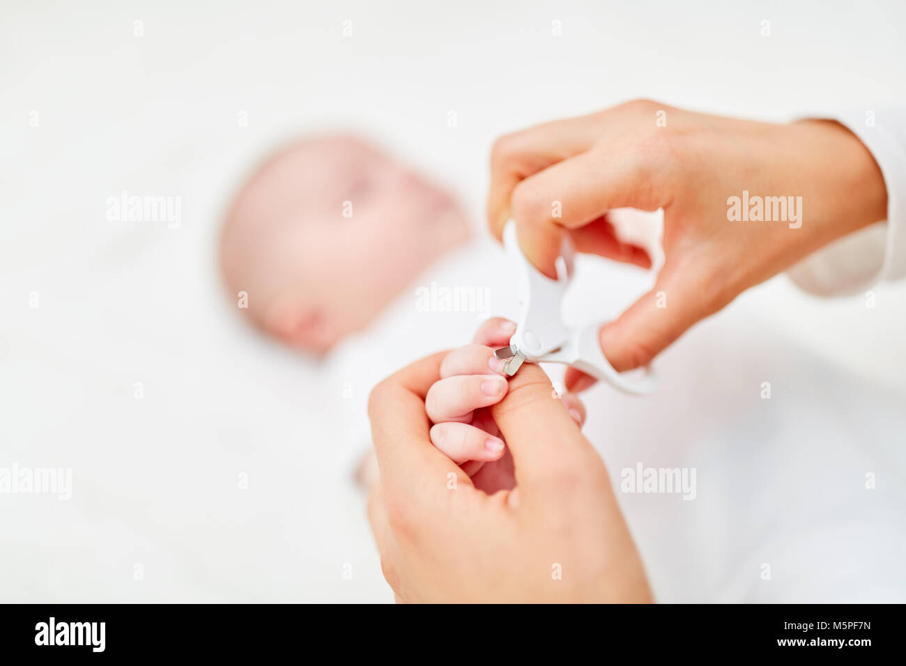 Mother makes careful nail care on her newborn baby Stock Photo
