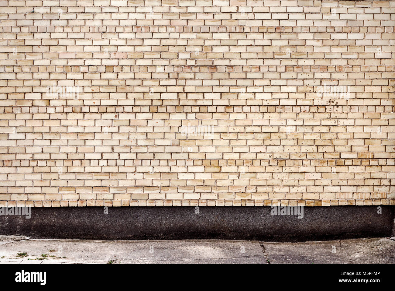 Yellow brick wall background with concrete basement. Architecture