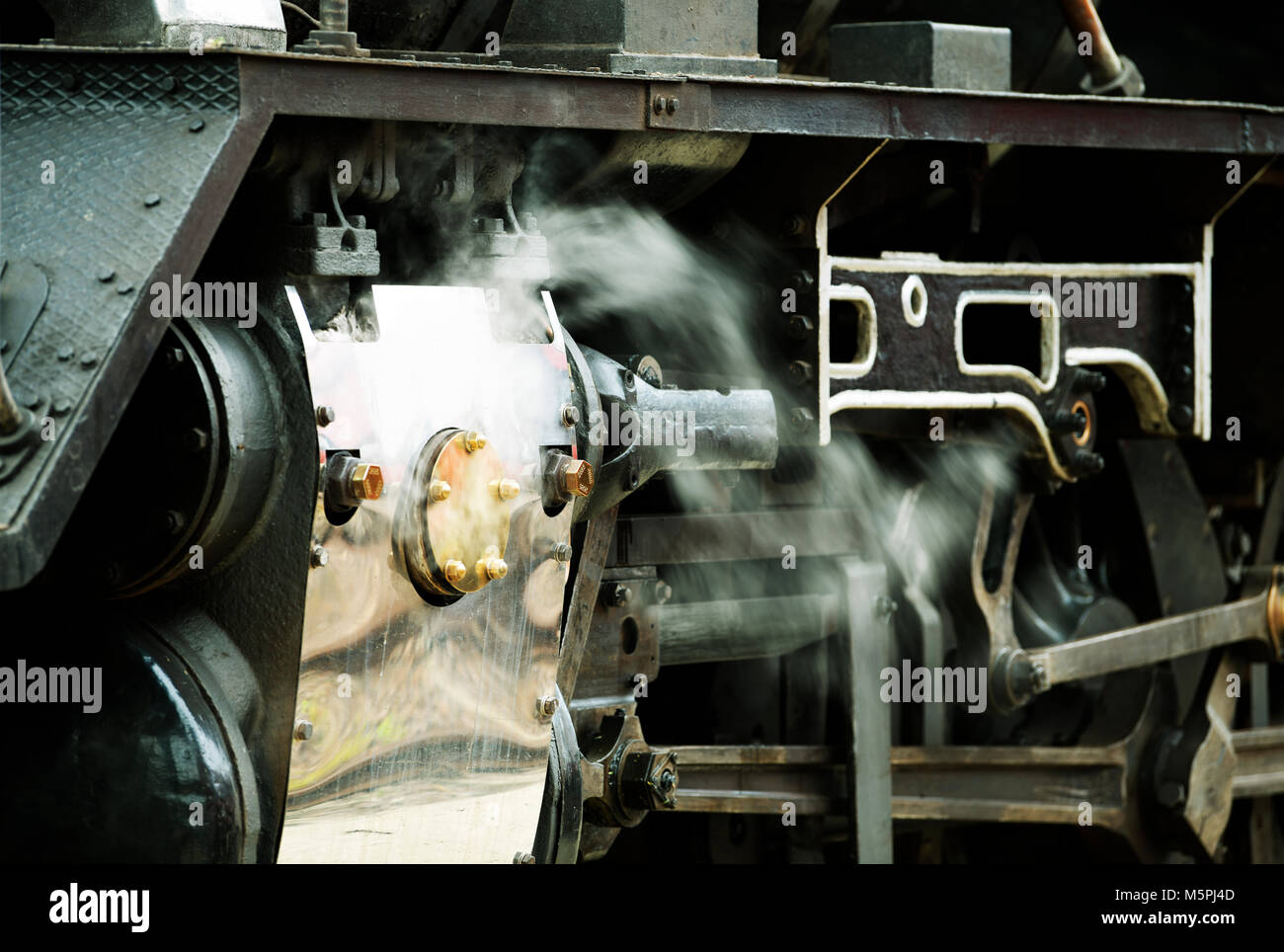 Steam escaping from release valves on the drive train of a refurbished vintage steam locomotive Stock Photo
