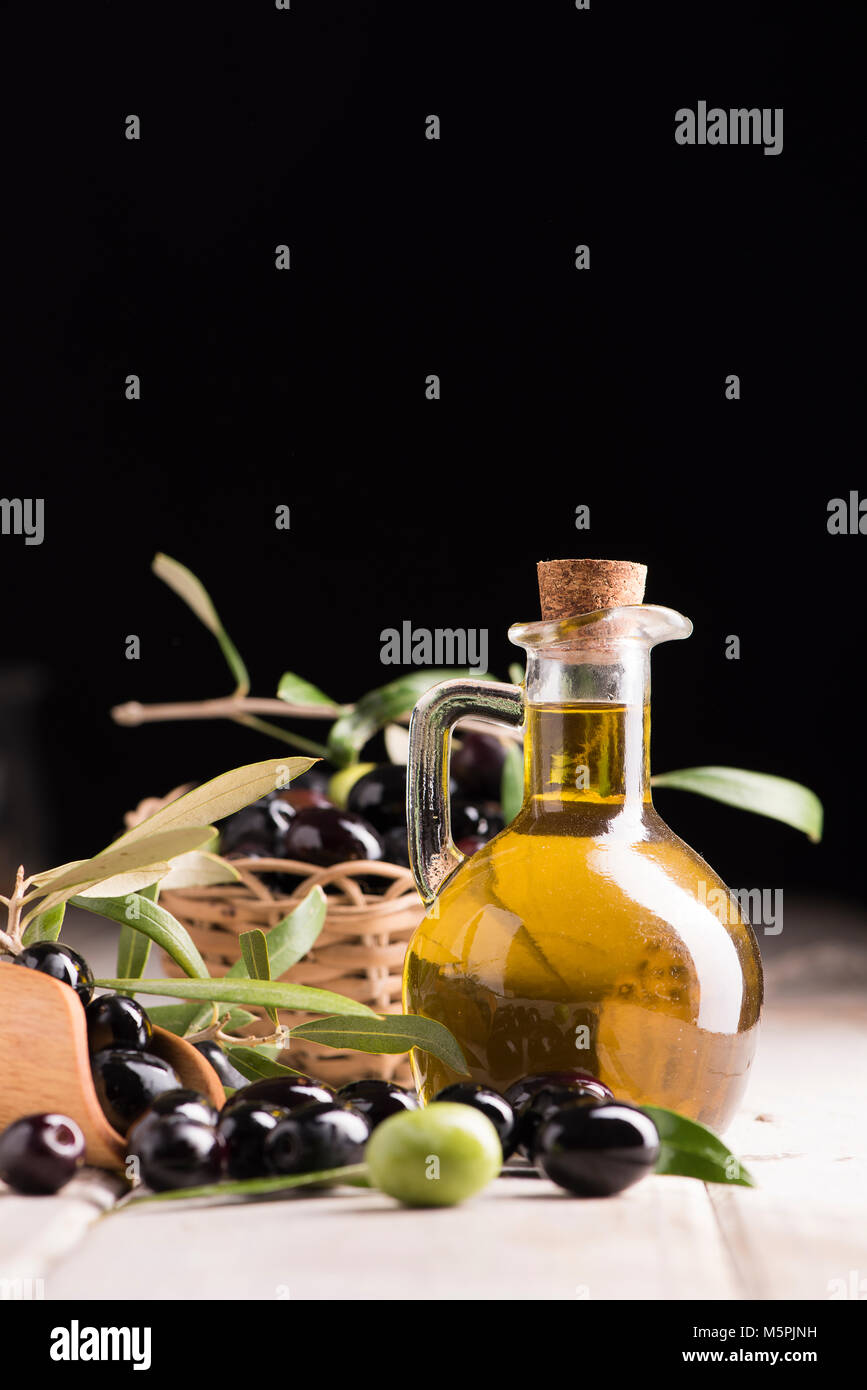Olives and a bottle of olive oil on white dark wooden table Stock Photo ...