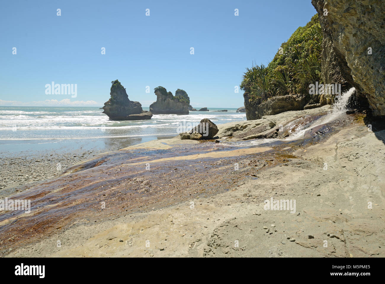 A fresh water stream spills out on to a West Coast beach, South Island, New Zealand Stock Photo
