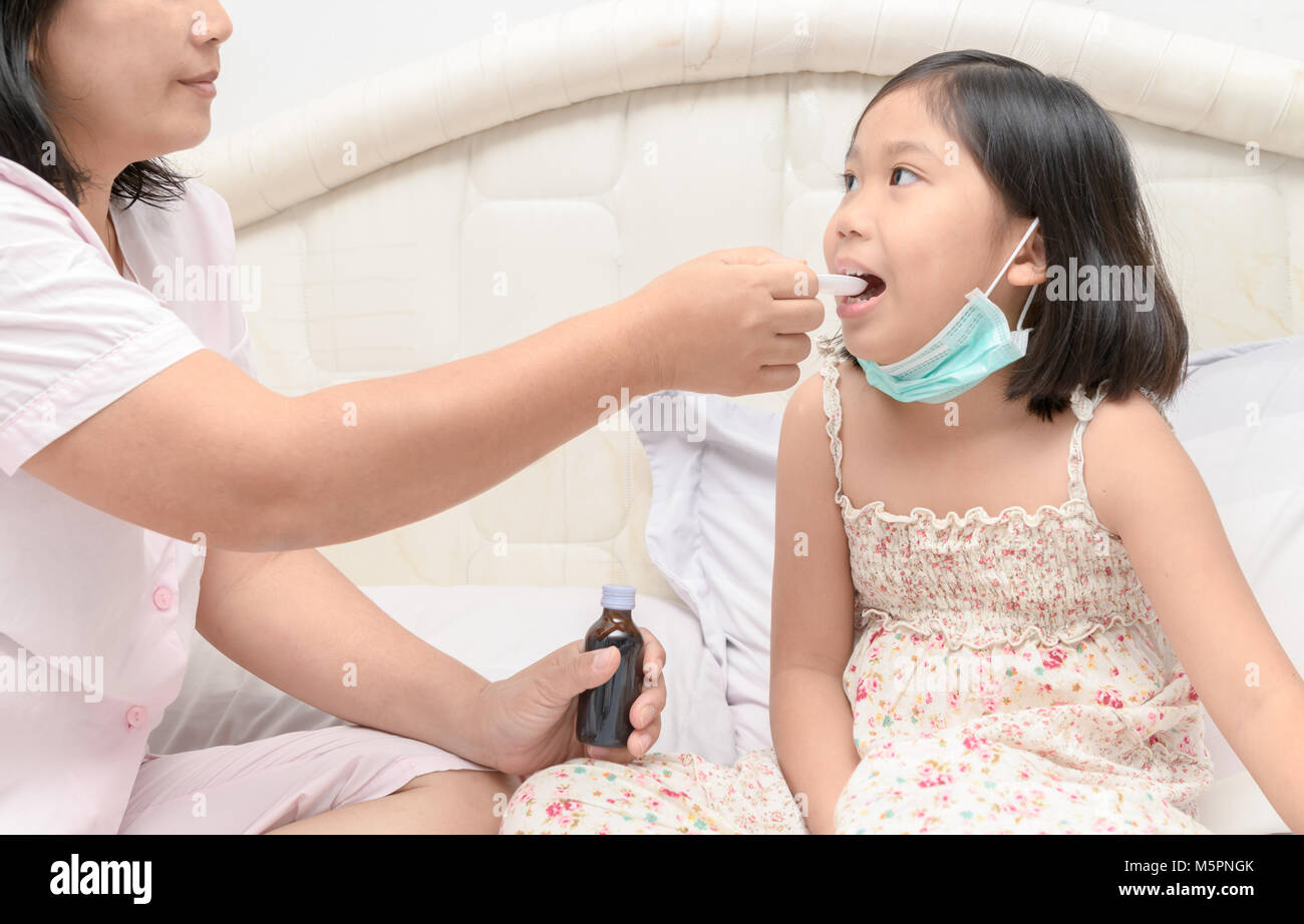 Mother giving her daugther syrup because of the flu and cough, Health care concept Stock Photo