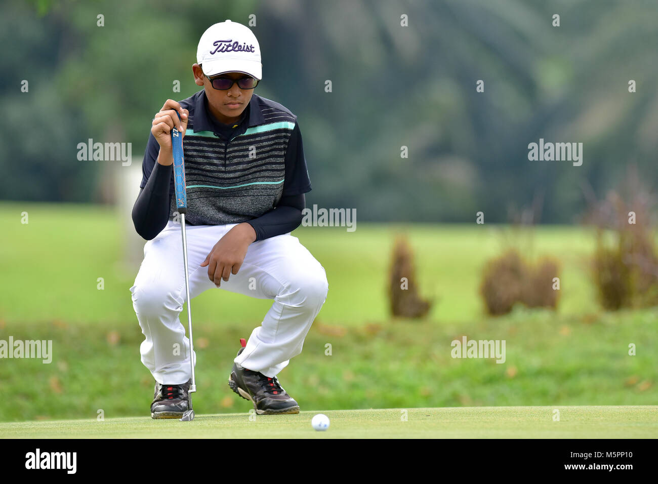 Danau, UKM Bangi - FEBRUARY 11: Vishnu Raja lines up his putt on the 5th green during Final Round of the Danau Junior Championship at Danau Golf Club  Stock Photo