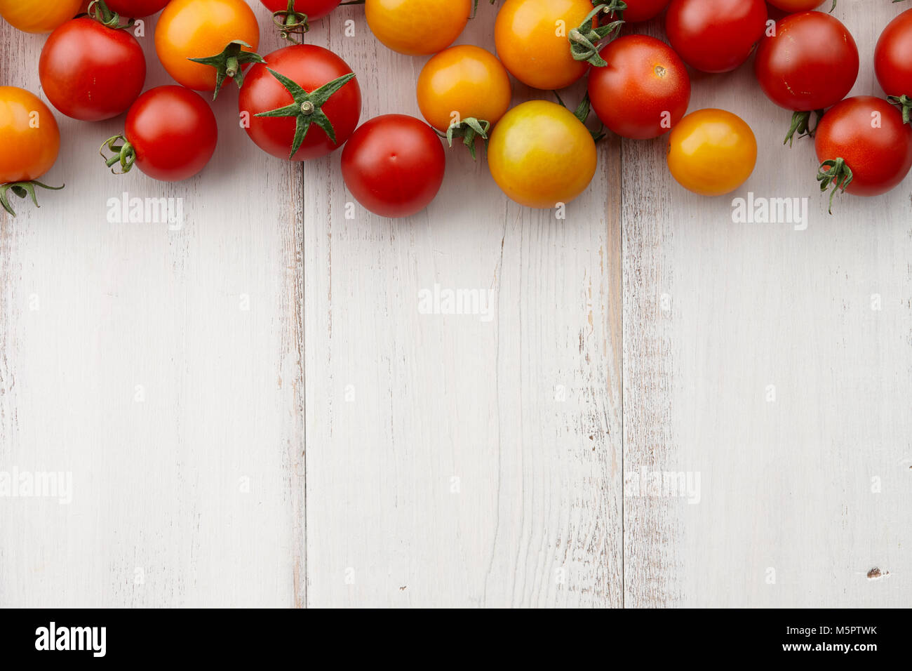Bright red and yellow tomatoes on white wooden table, top view Stock ...