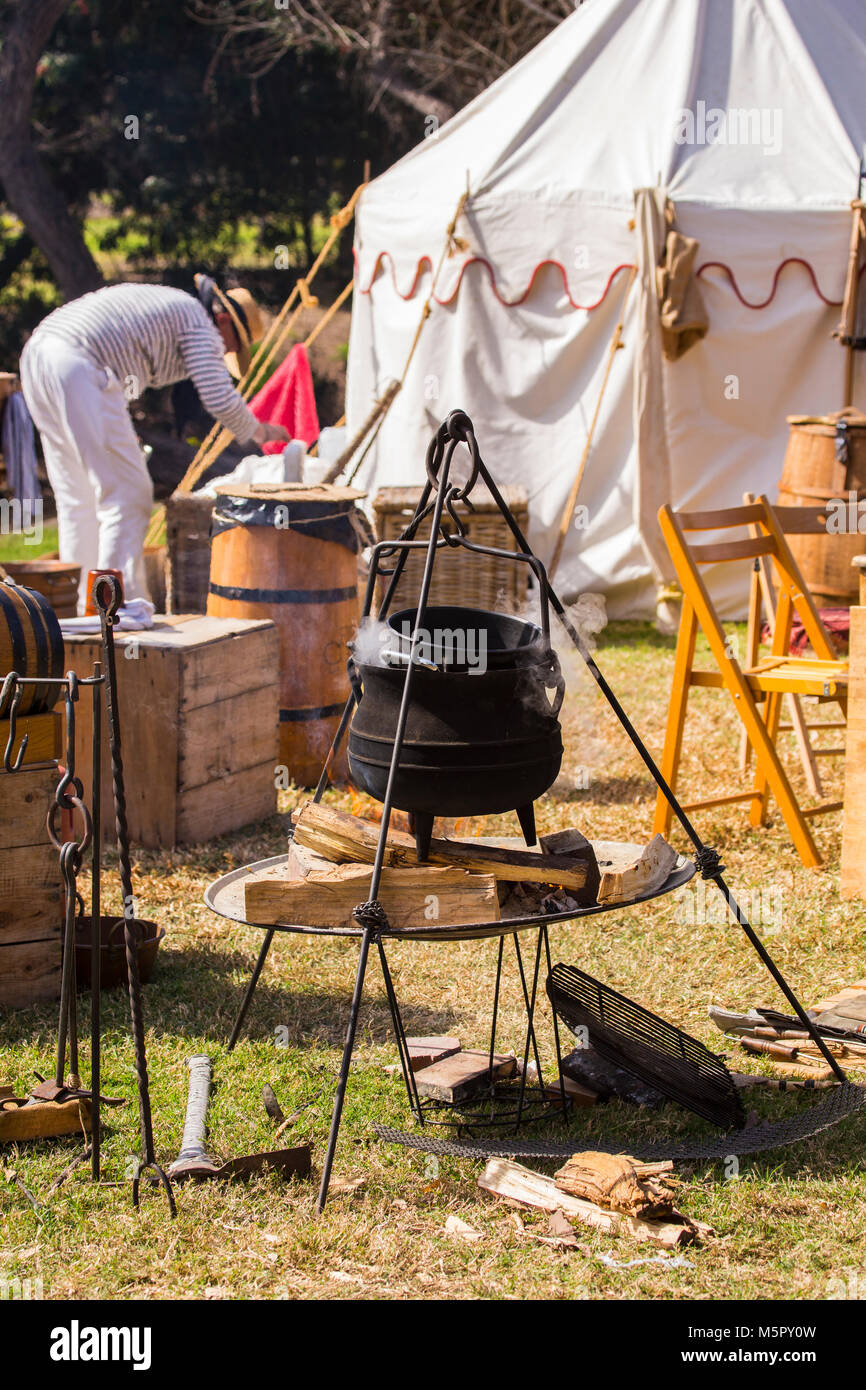 Outdoor cooking in a cast iron pot over an open wood campfire at a