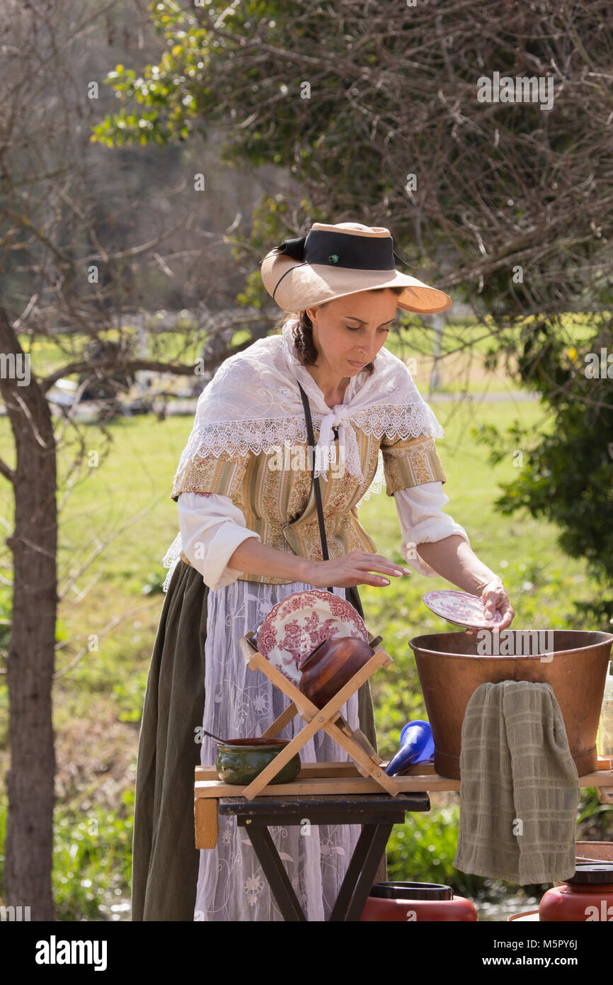 A woman in period dress hand  washing plates and dishes at a American revolution reenactment event in Huntington Beach California USA Stock Photo