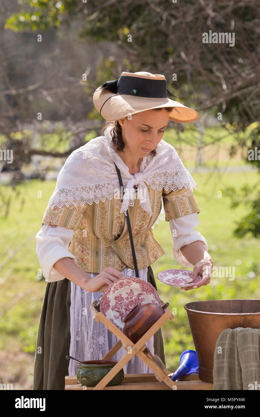 A woman in period dress hand  washing plates and dishes at a American revolution reenactment event in Huntington Beach California USA Stock Photo