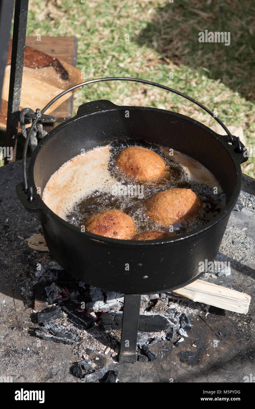 Deep frying golden brown scotch eggs outdoors over an open wood fire in