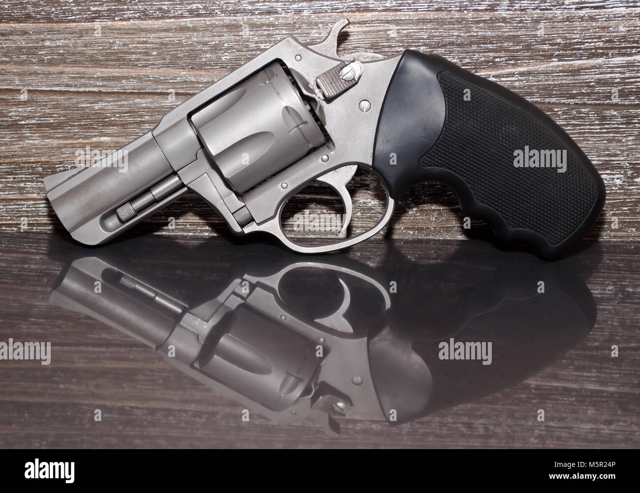 A stainless steel 44 special magnum revolver on a reflective surface with a  wooden background Stock Photo - Alamy