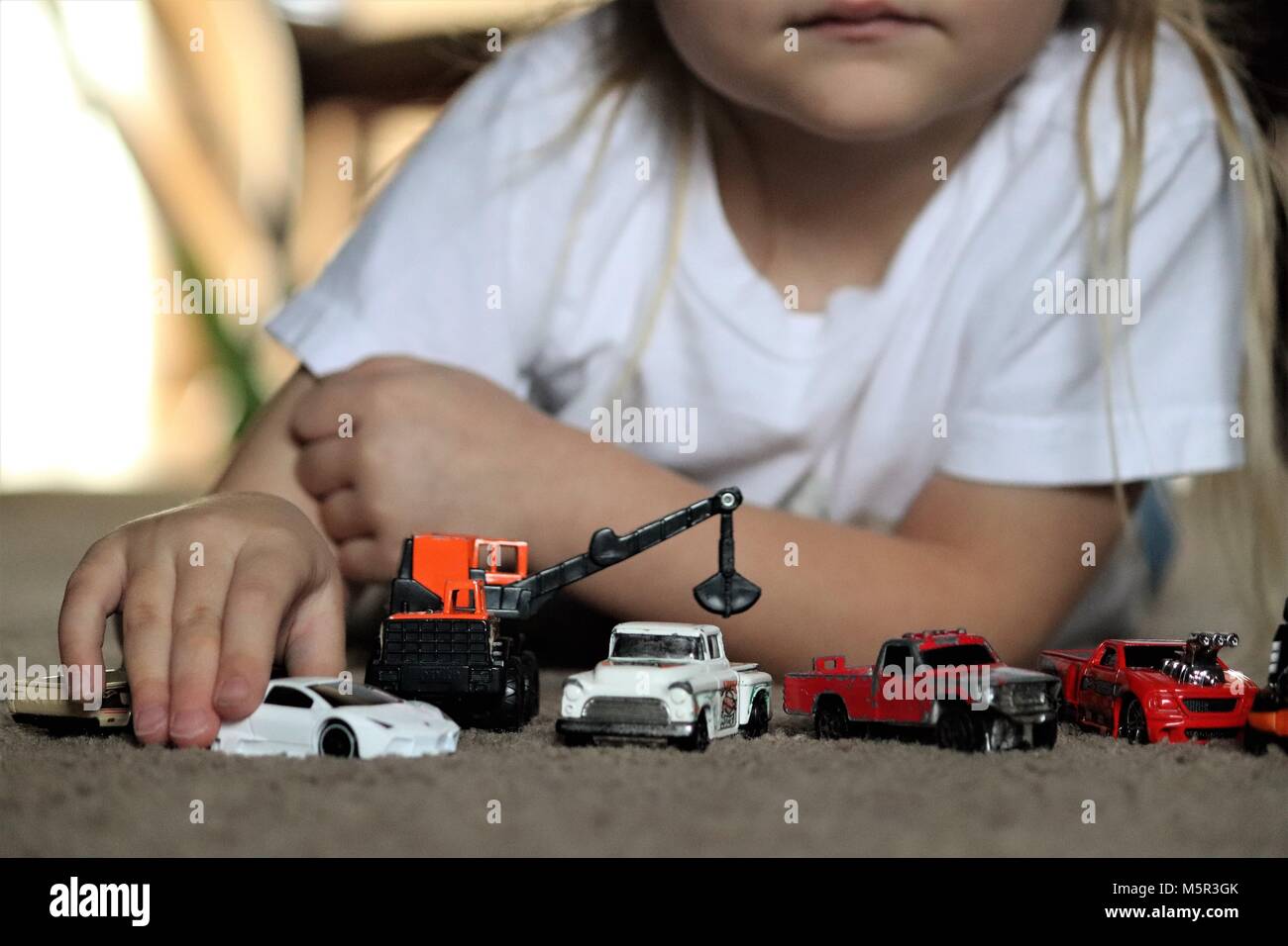 Girl enjoys playing with her toy cars Stock Photo