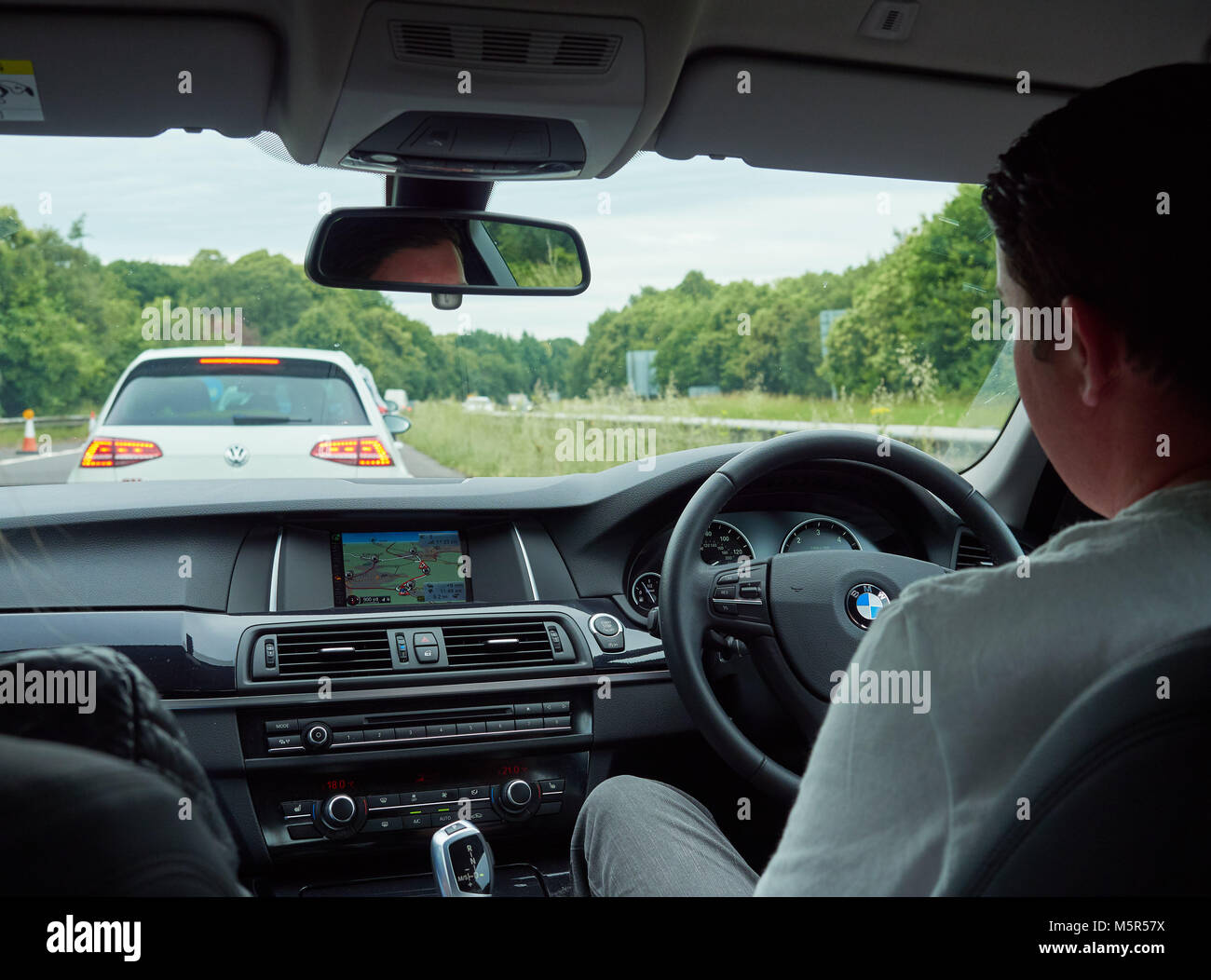 A car interior and driver of a car stuck in traffic from roadworks on a motorway. Stock Photo