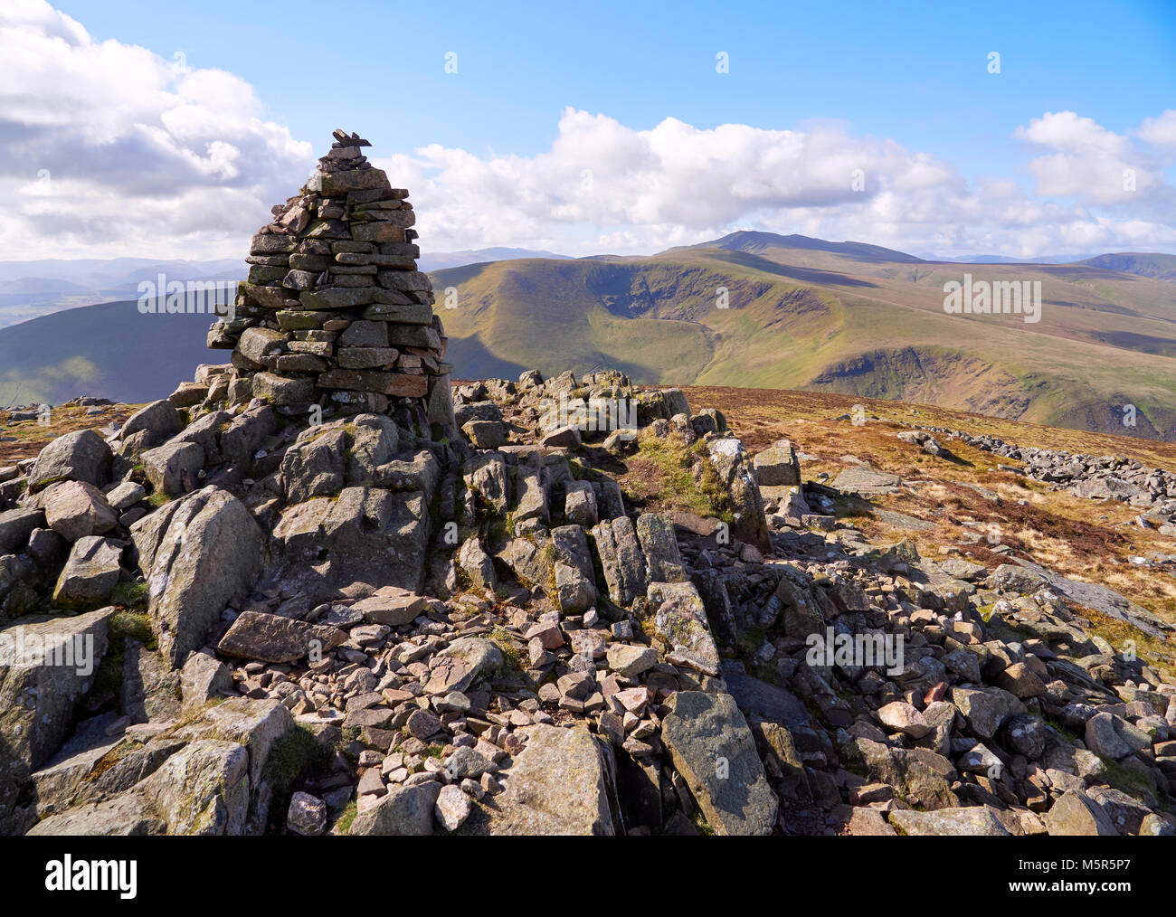 The summit cairn (pile of stones) of Carrock Fell with Bowscale Fell and Blencathra in the distance in the English Lake District, UK. Stock Photo