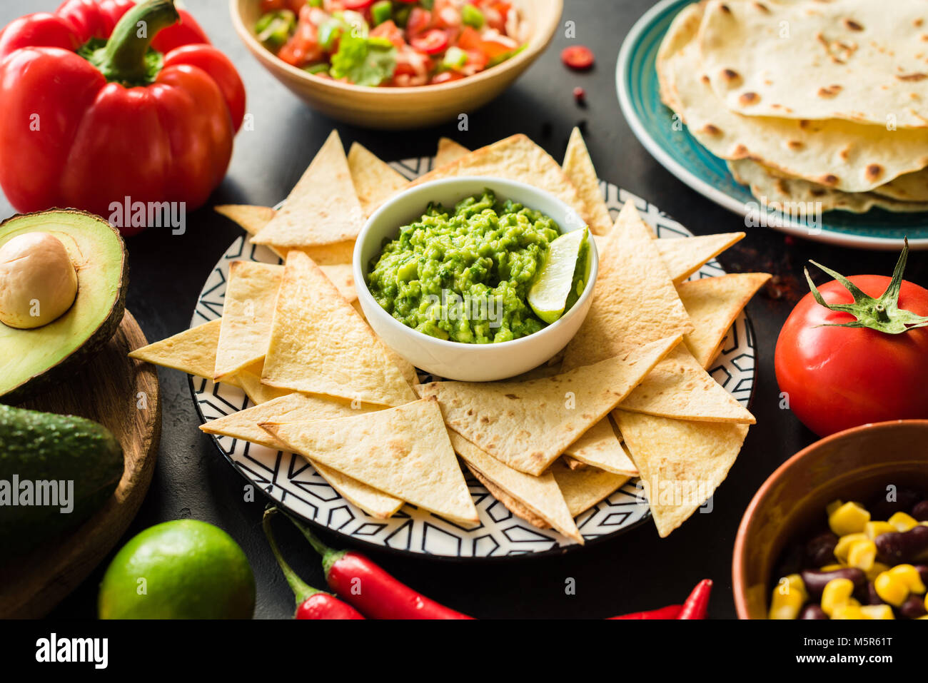 Mexican food Guacamole Nachos Tortilla chips salsa and beans on dark table. Food plate, Mexican