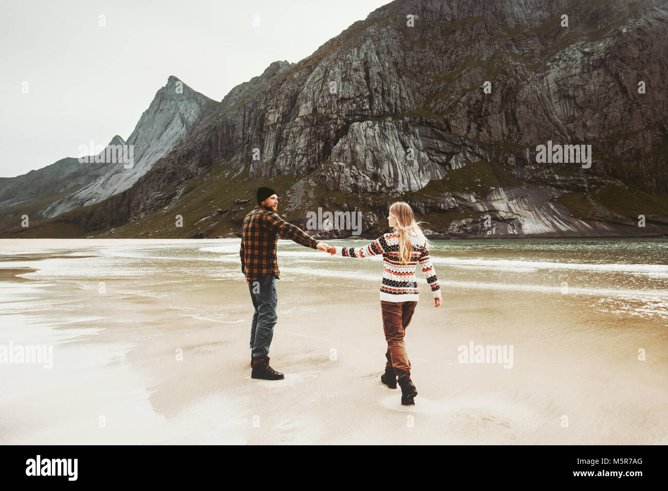 Couple walking together on beach holding hands Man and Woman together traveling Lifestyle concept romantic vacations at northern sea Stock Photo