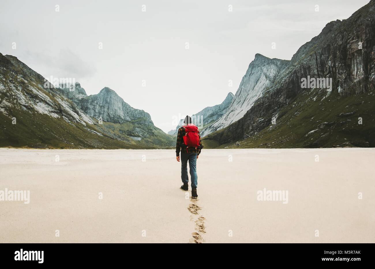 Man with red backpack walking alone at Horseid beach in Norway Travel lifestyle concept adventure outdoor summer vacations wild nature Stock Photo