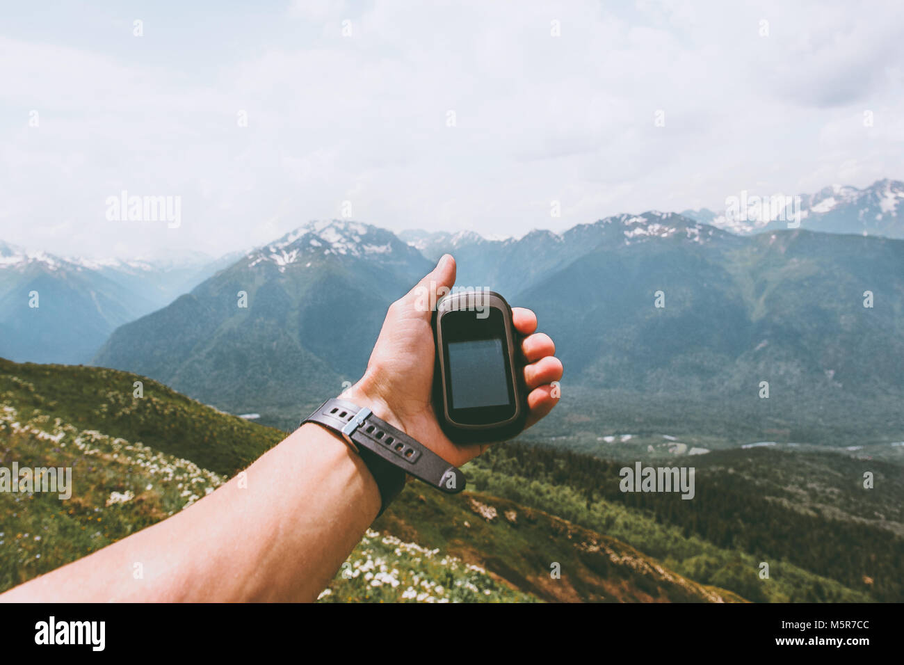 Traveler hand holding gps navigator tracker looking for location coordinates hiking in mountains