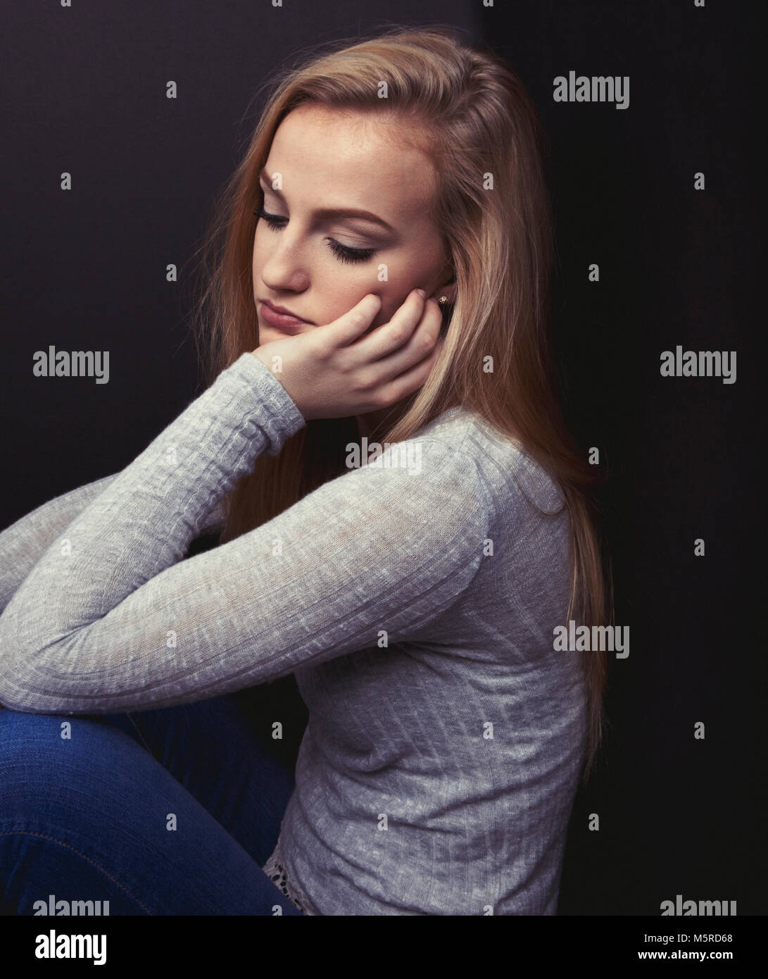Blond teenage girl looking sad resting her head on her hand Stock Photo ...