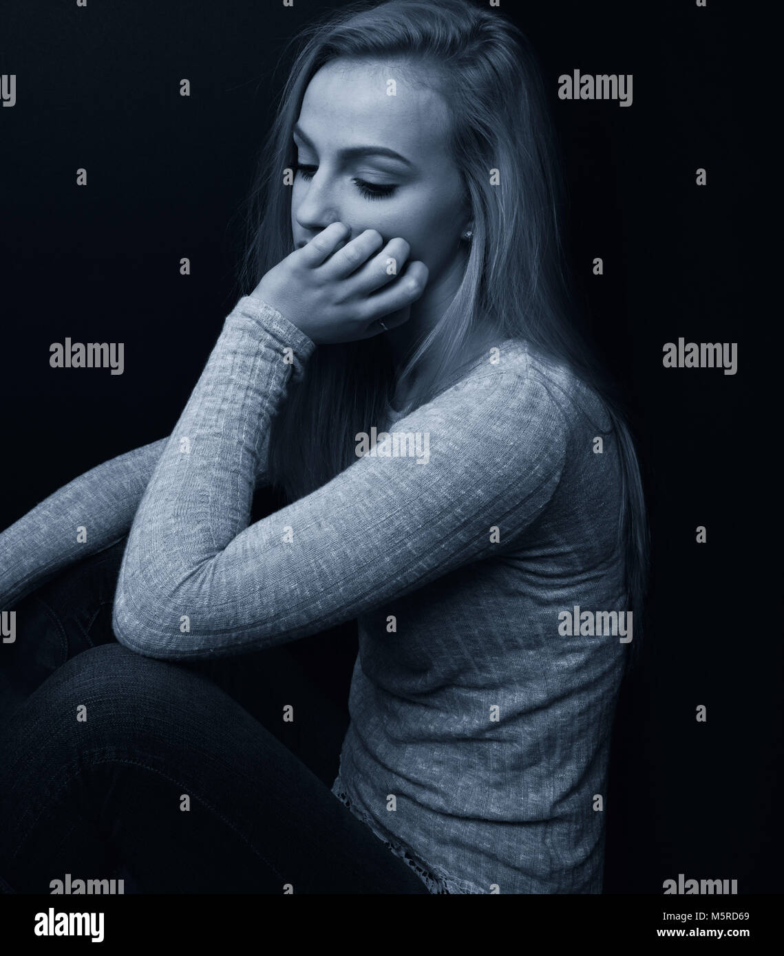 Pretty blond teenage girl looking sad with one hand on her face Stock ...
