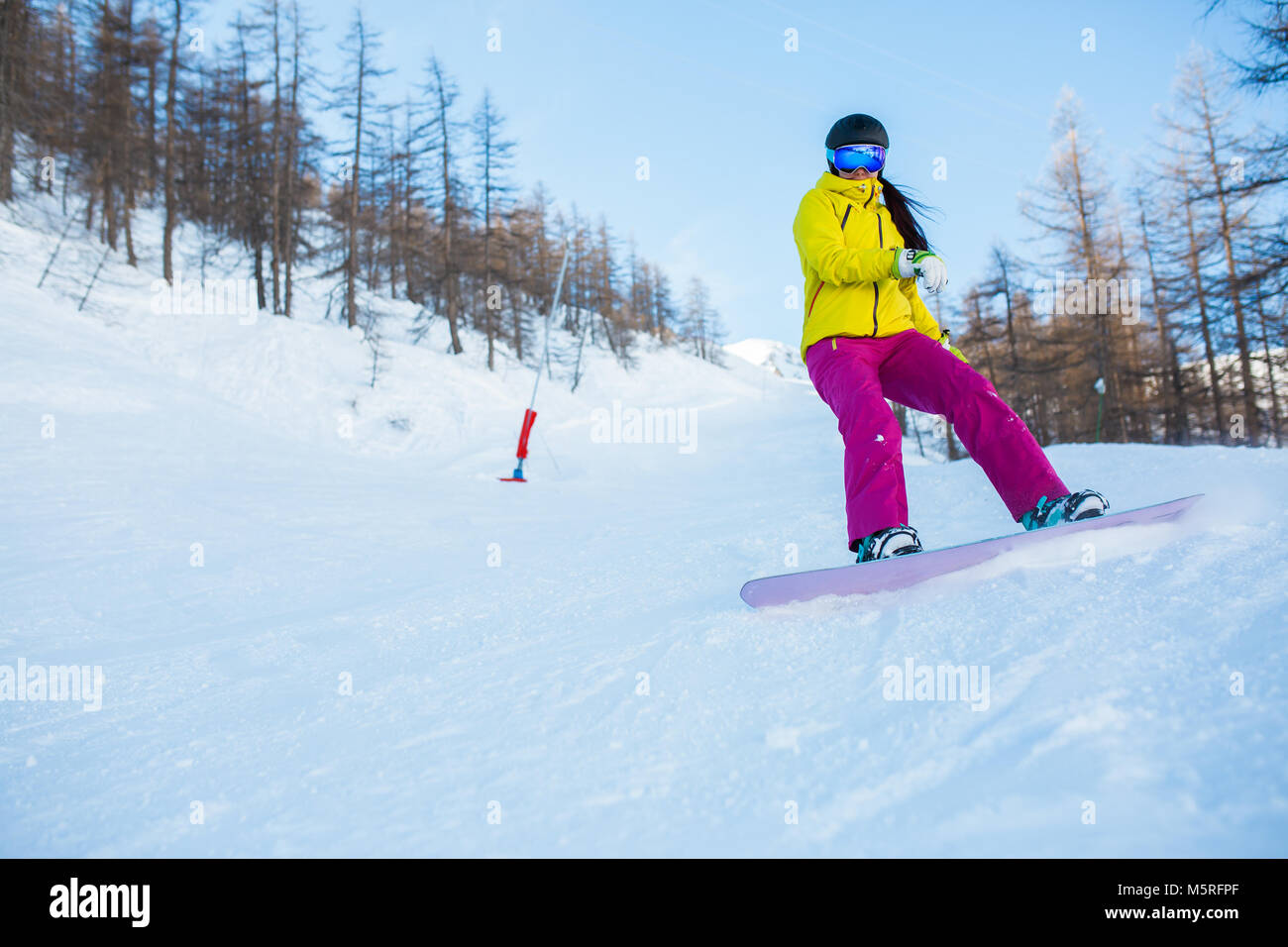 Image of female athlete wearing helmet and mask snowboarding from snowy