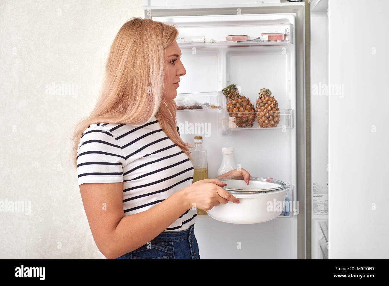 woman is standing in front of the fridge and thinks what to eat Stock Photo