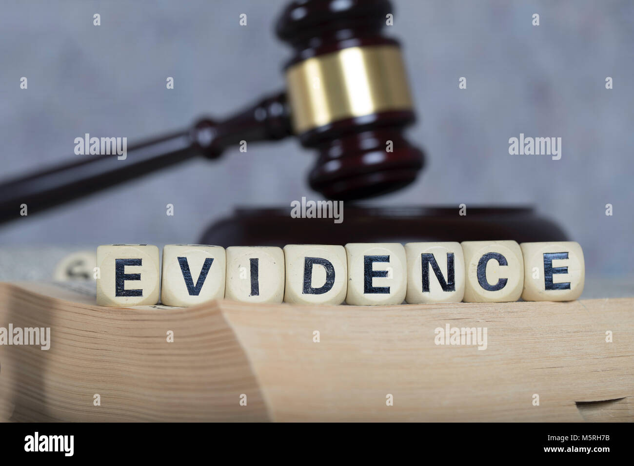 Word EVIDENCE composed of wooden letters. Statue of Themis and judge's