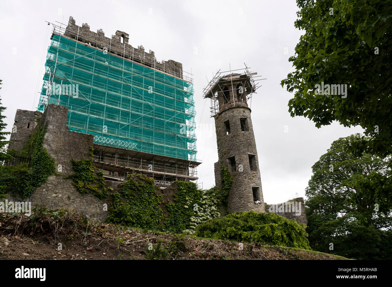 Blarney Castle covered in scaffolding during restoration work at Blarney near Cork in Southern Ireland.   Visitors climb the steps to the top of the c Stock Photo