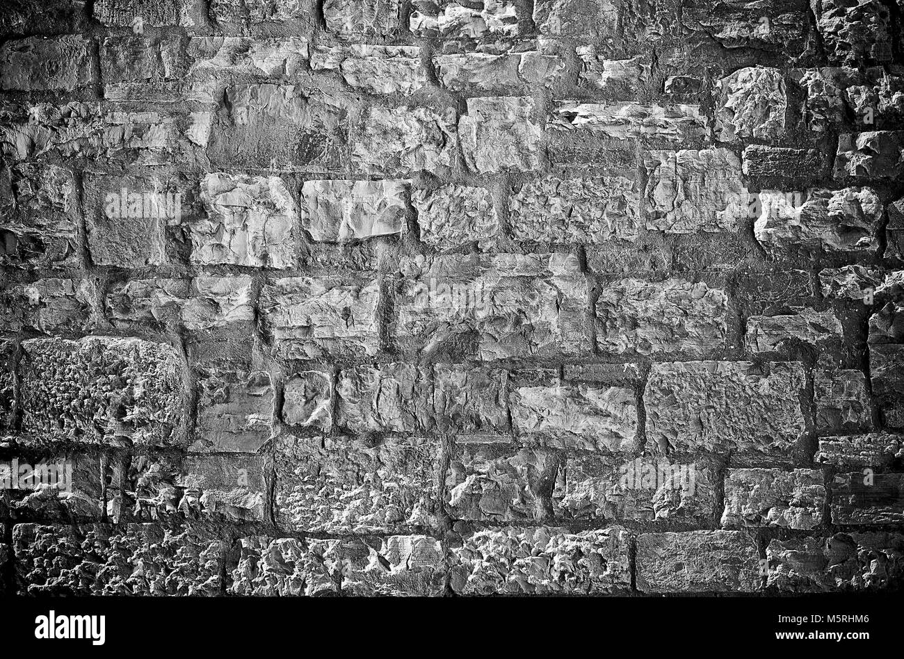 Rough textured limestone brick wall black background Stock Photo