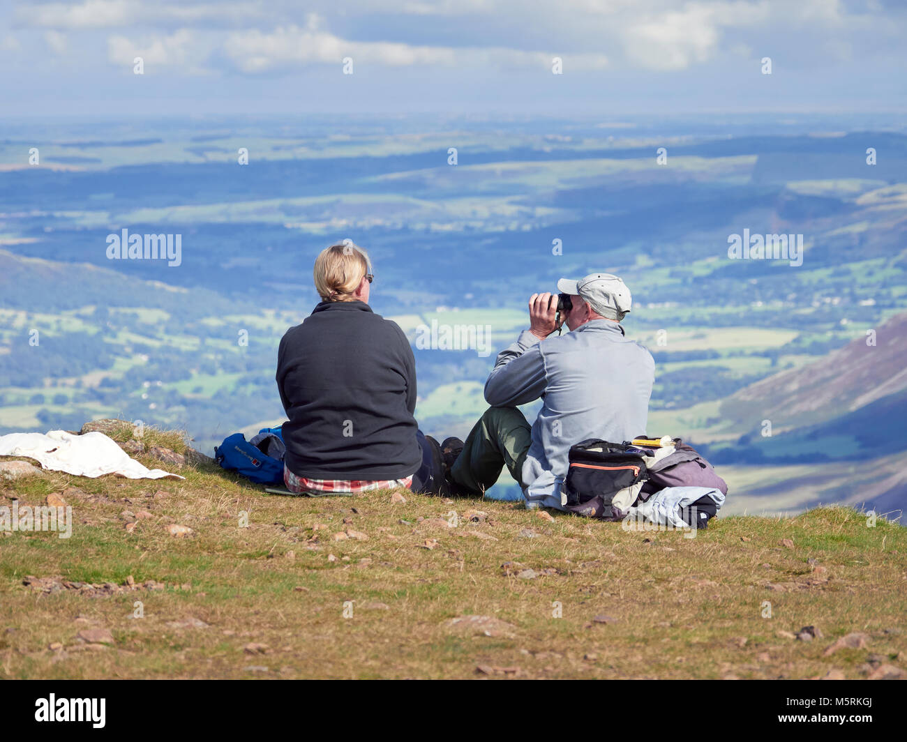 LAKE DISTRICT, CUMBRIA, ENGLAND, UK - SEPTEMBER 02, 2017: A male and female hiker sat down resting on the summit of Red Pike taking in the views over  Stock Photo
