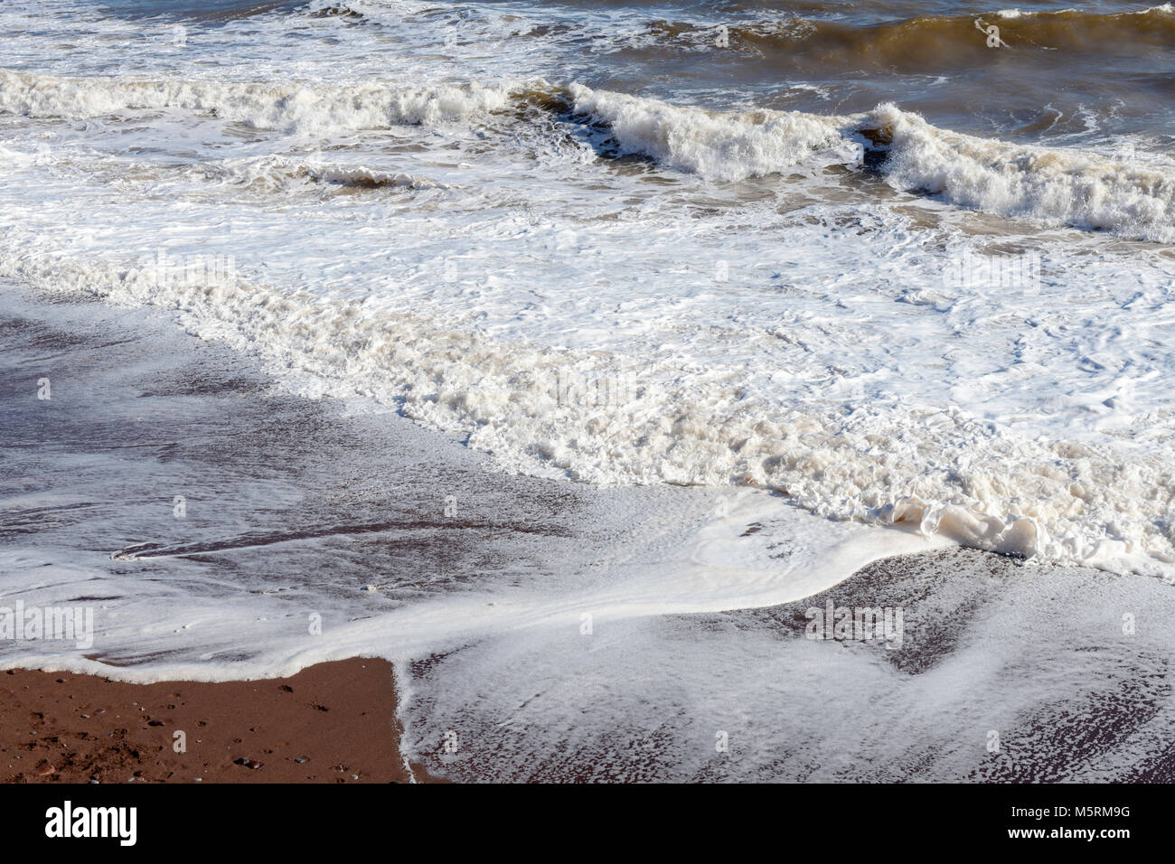 Sea waves and foam breaking on beach at Ness cove Shaldon south Devon UK Stock Photo