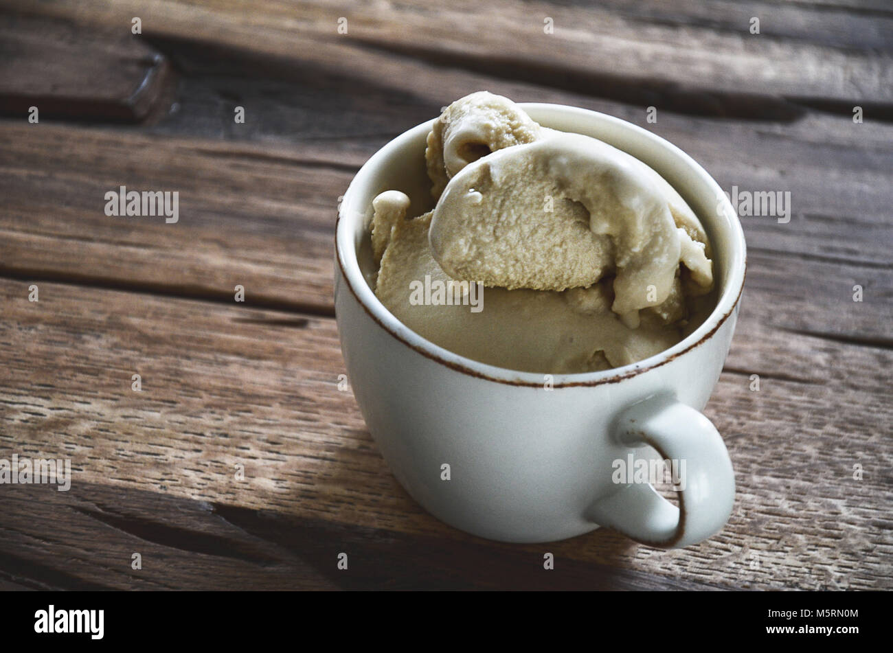 White coffee cup filled with soft coffee flavoured ice cream on dark