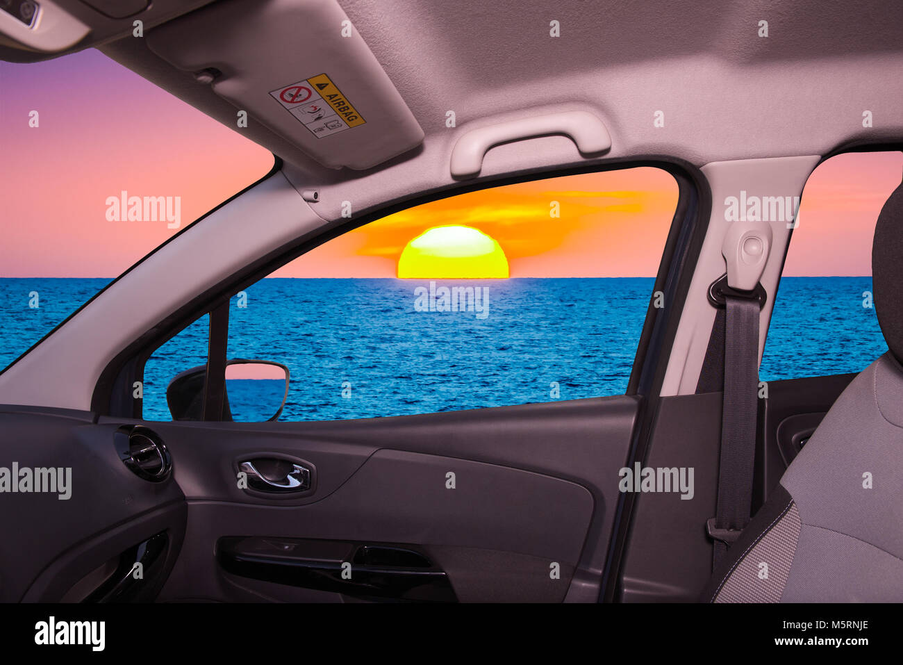 Looking through a car window with view of a scenic sunset by the mediterranean sea, Italy Stock Photo