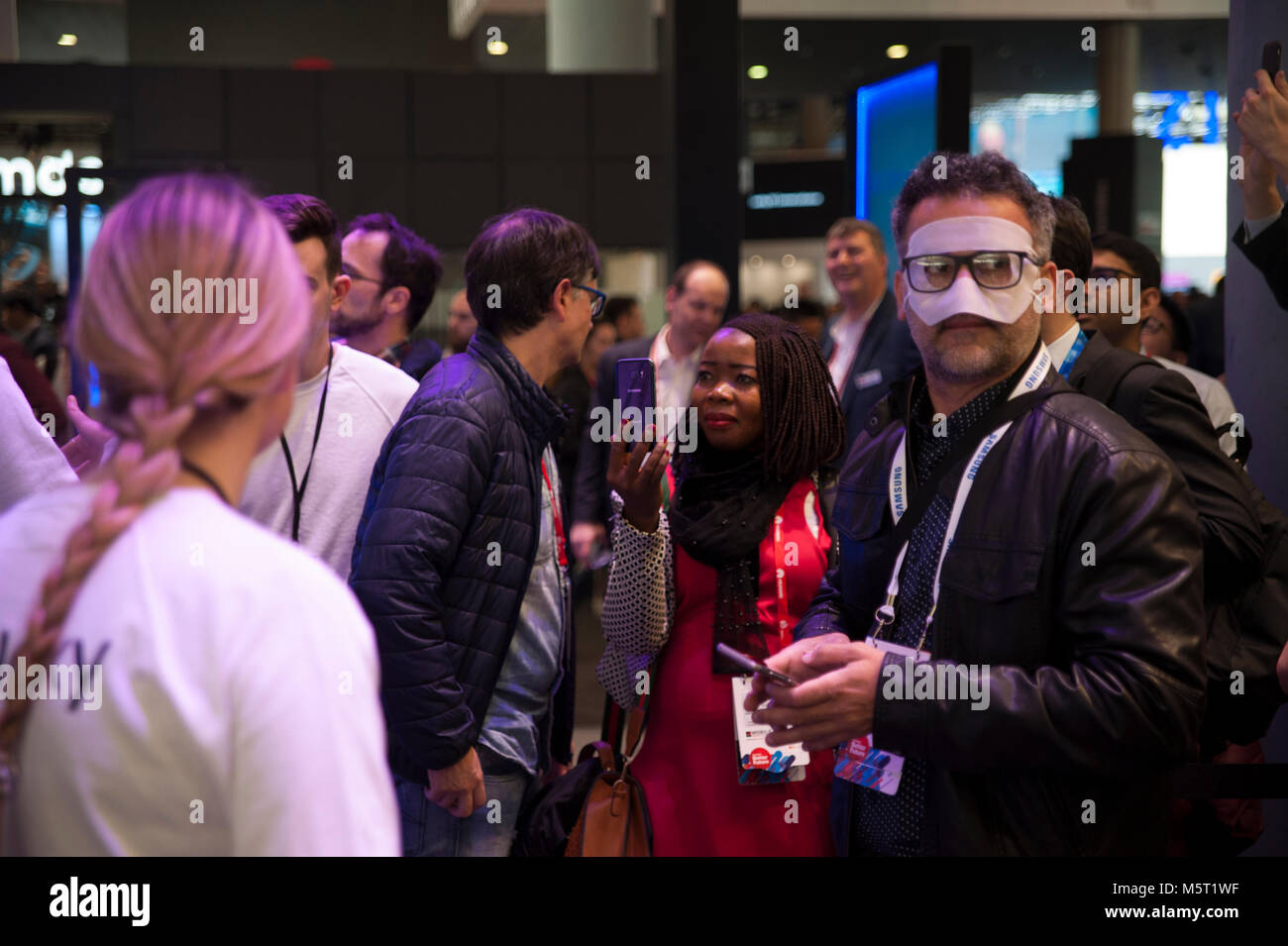 Barcelona, Spain. 26 Feb, 2018.  An attendant at the Mobile World Congress awaits her turn to try Samsumg's virtual reality glasses with a mask on her face for the most igienic use of glasses. The congress begins this Monday in Barcelona and has overcome the success of the last edition. Credit: Charlie Perez/Alamy Live News Stock Photo
