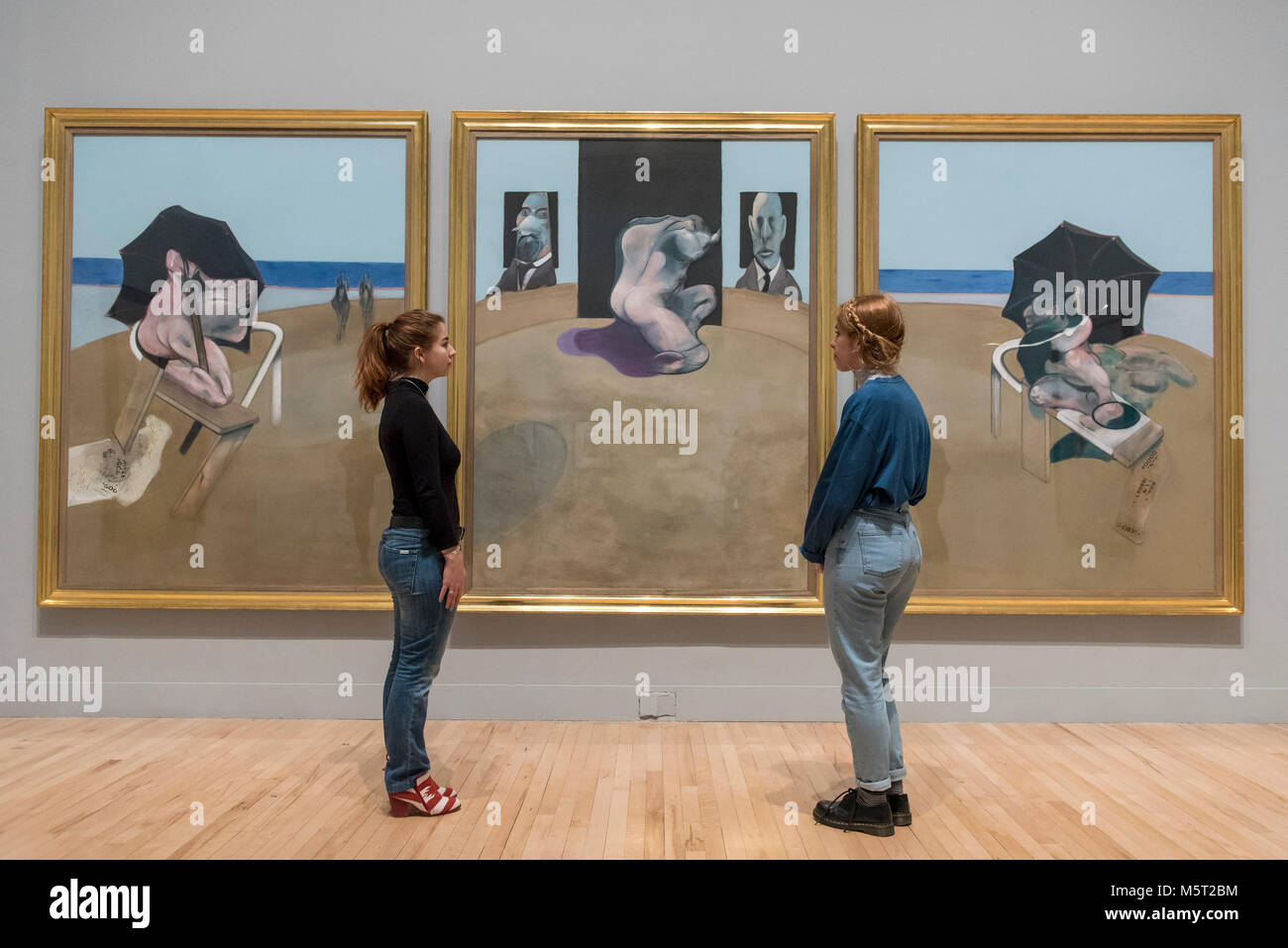 London, UK.  26 February 2018. Staff members stand with 'Triptych', 1974-1977, by Francis Bacon.  Preview of 'All Too Human', an exhibition at Tate Britain which explores how artists in Britain have stretched the possibilities of paint in order to capture life around them.  The exhibition runs 28 February to 27 August 2018 and includes rarely seen works by Lucian Freud and Francis Bacon.  Credit: Stephen Chung / Alamy Live News Stock Photo